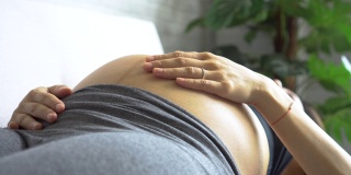 快乐的亚洲孕妇在运动服装触摸婴儿的肚子里