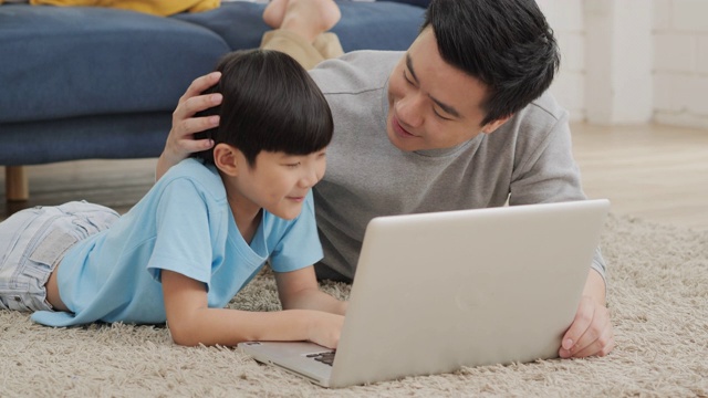 父子在家里一起使用电脑，心情愉快。家庭、科技和生活理念。