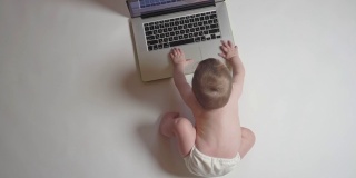可爱的宝宝看着笔记本电脑，教育理念。俯视图