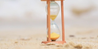 沙漏时钟上的热带沙滩时间仪器。手表手表过去的历史老式埋葬在沙滩在阳光灿烂的日子。