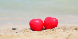 热带夏日沙滩上的两颗红心。情人节象征情侣概念。