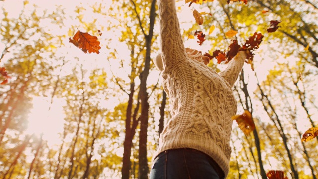 MS超级慢镜头无忧无虑的年轻女子纺纱在飘落的金秋树叶在森林