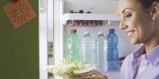 从冰箱里拿出健康蔬菜的女人