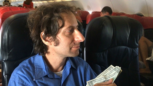 一位沮丧的旅行者在飞机上用现金买东西时遇到了困难