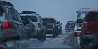 黄昏时分，暴风雪期间，在州际公路上被事故和紧急救援人员拦下时，从一辆车的前面拍摄的