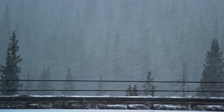 在冬季暴风雪期间，在科罗拉多州的落基山脉70号州际公路上缓慢行驶的车辆的侧面视图