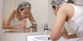 亚洲妇女在浴室用干净的水洗脸