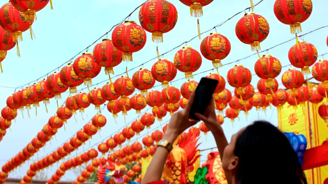 女人拍照的许多中国灯笼在神社。彩灯上的祝福文字寓意拥有财富和幸福