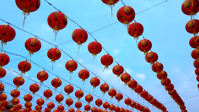 许多秋千中国灯笼装饰中国新年与蓝天背景。彩灯上的祝福文字寓意拥有财富和幸福