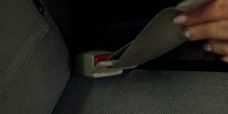 一个女人的手在一辆车系安全带的特写。