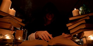中近距离的女孩魔术师在一个黑暗的房间在烛光下寻找一个咒语翻书。低调。神秘的小景深