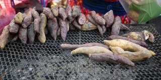 美味的烤制有机红薯紫色和黄色的木炭炉在新鲜市场在冬季。