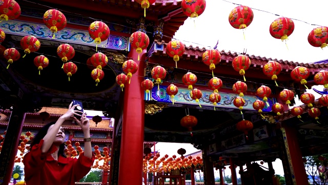 女人拍照的许多中国灯笼在神社。彩灯上的祝福文字寓意拥有财富和幸福