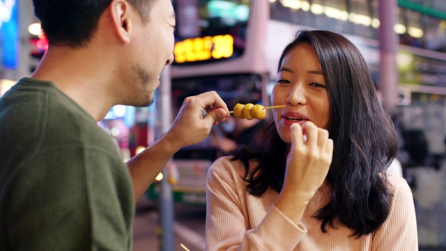 SLO MO手持中景拍摄一对年轻夫妇在香港街头吃小吃