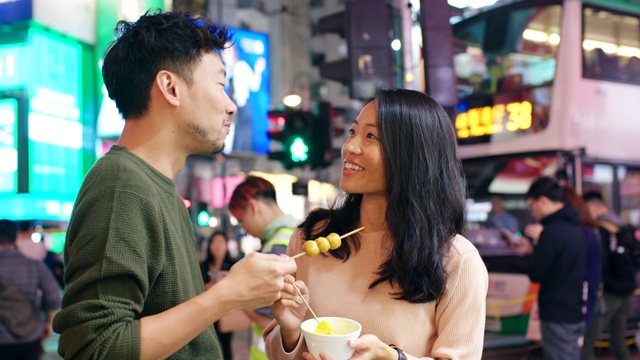 SLO MO手持中景拍摄一对年轻夫妇在香港街头吃小吃