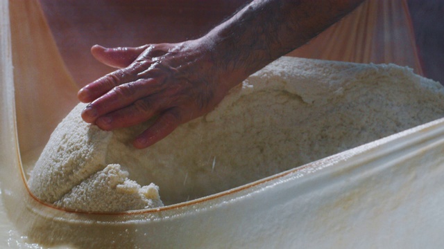 慢镜头近距离拍摄的一个奶酪制作者正在准备一种形式的帕尔玛奶酪使用新鲜和生物牛奶遵循古老的意大利传统