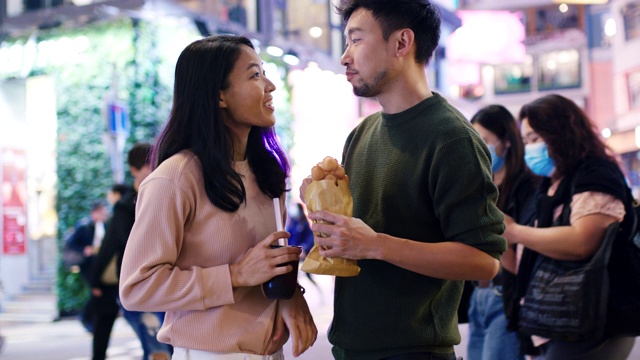 SLO MO手持中景拍摄一对年轻夫妇在香港吃传统街头小吃