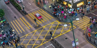 在中国香港尖沙咀地区，人们和出租车穿过一个非常繁忙的十字路口