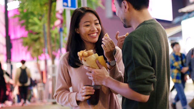 SLO MO手持中景拍摄一对年轻夫妇在香港吃传统街头小吃