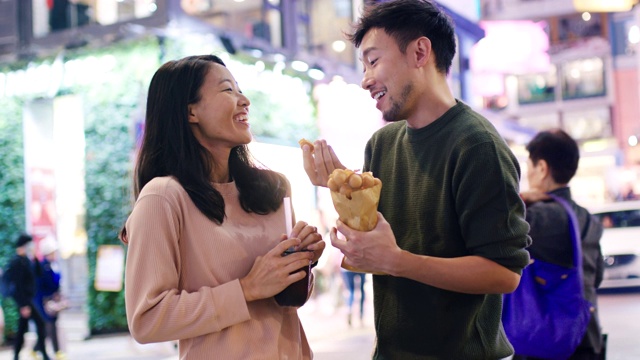 SLO MO手持中景拍摄一对年轻夫妇在香港吃传统街头小吃