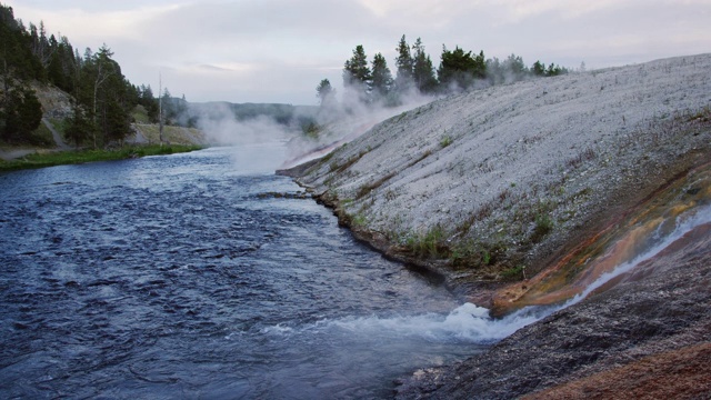 在怀俄明州的黄石国家公园，水在大棱柱形泉的岩石表面和进入蒸汽的火洞河的慢动作拍摄