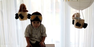 可爱的蹒跚学步的男孩，玩飞机和泰迪熊，气球和身后的玩具
