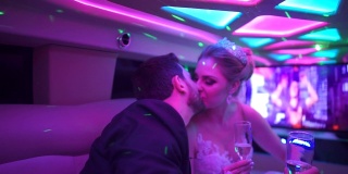 新娘和新郎在去参加婚礼的路上在豪华轿车里接吻