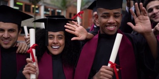 一群年轻的大学毕业生都拿着他们的毕业证书，在镜头前微笑着互相拥抱
