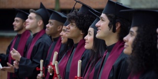 在毕业典礼上排队的毕业生们看向别处，而非洲裔年轻人看着镜头微笑