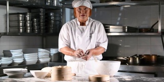一名亚洲妇女在餐厅厨房里包饺子