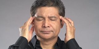 近距离观察老男人的压力，摩擦头部，头部，孤立在灰色背景。穿着黑衬衫的亚洲人。