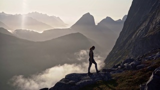 一名妇女在雾中Senja岛的山上徒步旅行视频素材模板下载