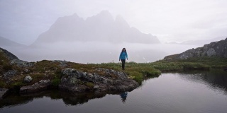 一名妇女在雾中Senja岛的山上徒步旅行