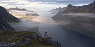 坐在雾中看着Senja岛的女人