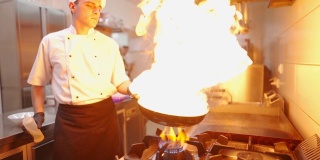 厨师在商业厨房的煤气炉上用平底锅准备火锅饭