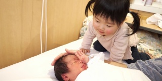 小女孩和妈妈一起照顾新生的婴儿