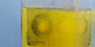 磁带漂浮在带有气泡、酸和毒药的黄色水中