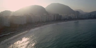 巴西里约热内卢科帕卡巴纳海滩的背光海洋航拍，午后的阳光和群山在背景中