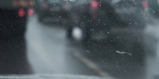 从驾驶室到挡风玻璃的视野。专注于前景。暴风雪期间汽车在赛道上行驶。冬季白天的降雪。恶劣的天气影响了交通。危险的旅行。手持拍摄的