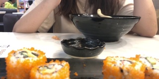 年轻的亚洲女人用筷子吃寿司，加州卷，日本食物