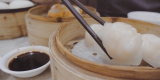 在香港的餐馆里，用筷子从蒸煮锅里拿热虾和酱汁