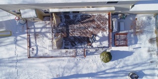 一名成年男子在一场冬季降雪后清理乡间小屋后院的露台。