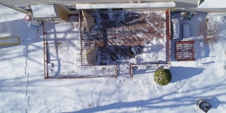 一名成年男子在一场冬季降雪后清理乡间小屋后院的露台。