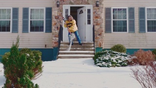 一个50岁的男人，长头发，穿着黄色夹克，正在清理一场冬季降雪后的门廊和楼梯。科勒,宾夕法尼亚州,美国视频素材模板下载