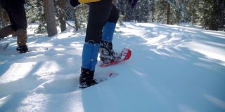 近距离慢动作拍摄的成年人徒步者脚雪鞋在深雪户外