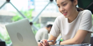 亚洲自由职业女性使用她的笔记本电脑和工作在咖啡店