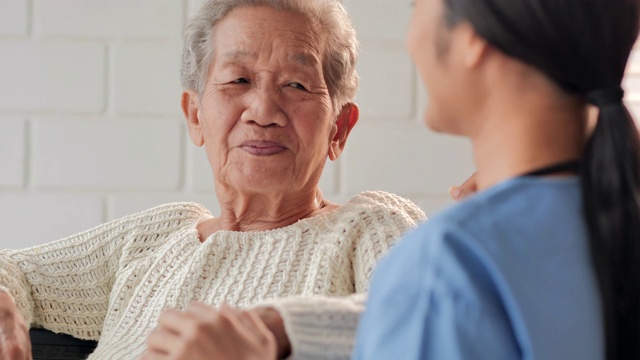 亚洲老年妇女与年轻的黑人女护士医生交谈，帮助患者接受医疗咨询教育，防止冠状病毒或Covid-19在家中流行。医疗:护理、教育、医疗、护理、志愿者、养老院、冠状病毒或新冠病毒