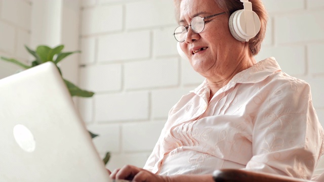亚洲老年妇女患者与医生在家里的电脑上进行视频会议。老年假期、技术、人、退休、生活方式、全球、医学教育、医疗咨询、医疗保健和医学概念。高级技术