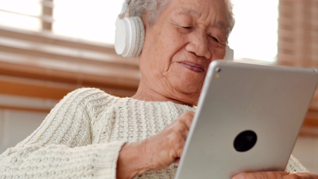 亚洲老年女性患者在家里用平板电脑与医生进行视频会议。老年假期、技术、人、退休、生活方式、全球、医学教育、医疗咨询、医疗保健和医学概念。高级技术