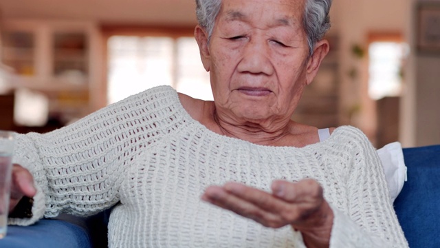 肖像亚洲老年妇女有一个感觉不舒服和服用药丸为她的健康或在家服用维生素。医疗，护理，退休，生活方式，医疗保健和医药，老年人保健，人寿保险，科学，药学概念，生病。
